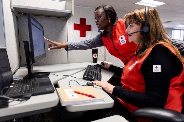 Two representatives in the American Red Cross Hero Care Center at Fort Sill, Oklahoma look over information on the computer screen in front of them.