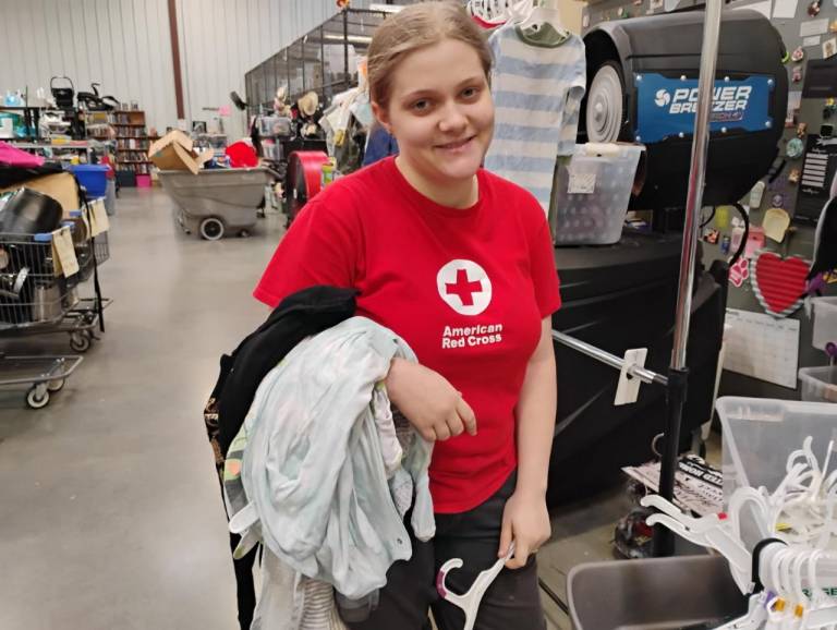A 17-year-old girl in a Red Cross shirt helps return clothes to their hangers at the Warrior Warehouse, a thrift store on the base.