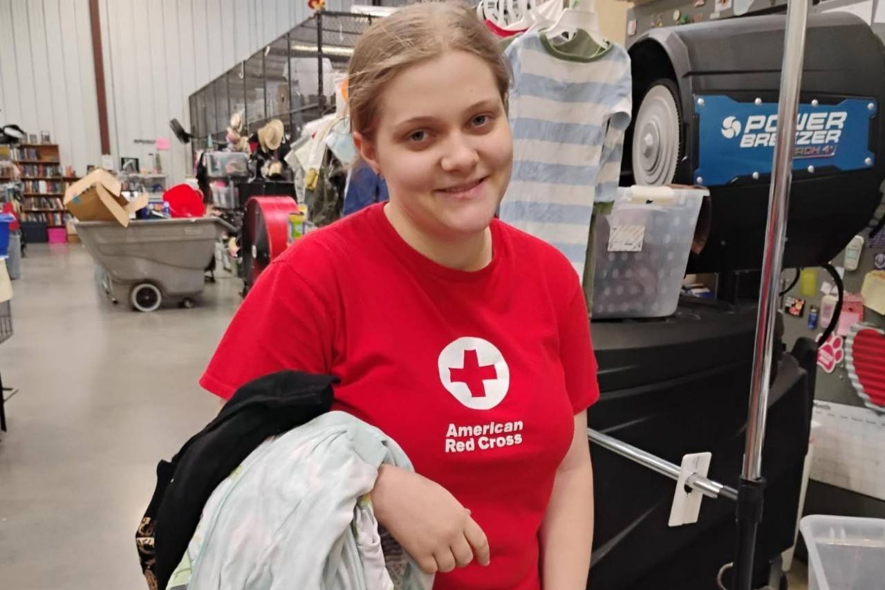 A 17-year-old girl in a Red Cross shirt helps return clothes to their hangers at the Warrior Warehouse, a thrift store on the base.