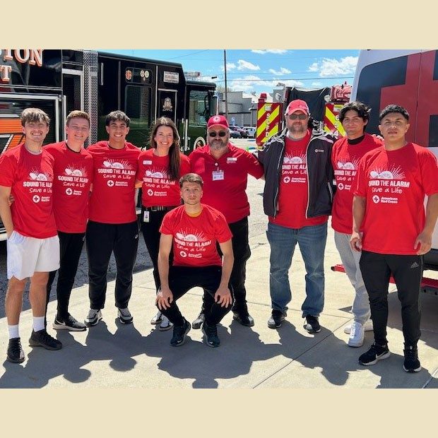 Group of Red Cross volunteers with fire engines in the background.