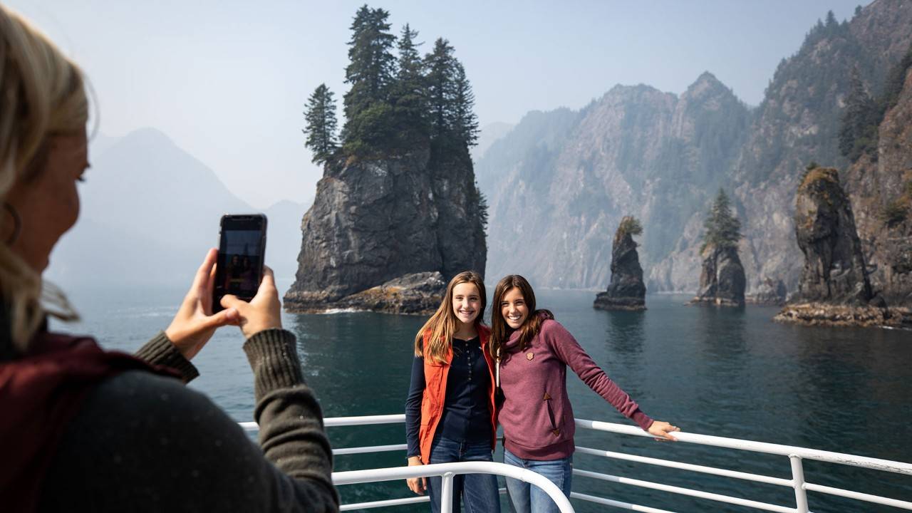 Two people on a cruise boat getting picture taken by person holding a smart phone.