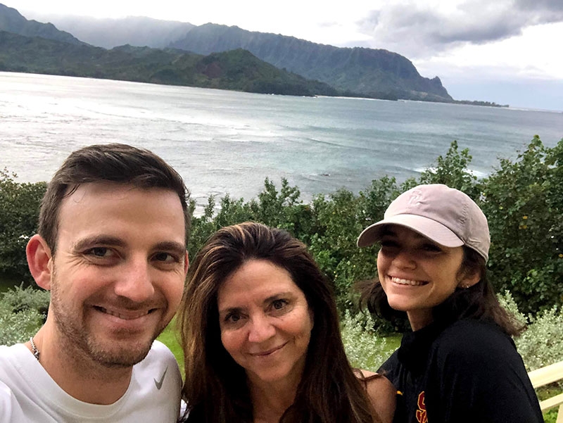 Eve Dreyfuss and two other people smiling for camera with with mountains and water in the background.