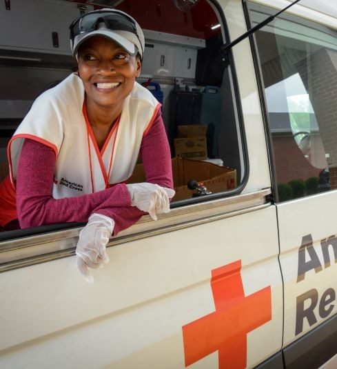Red Cross volunteer looking out of Red Cross van side window.