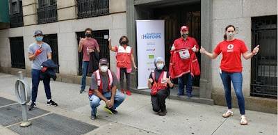 Red Cross volunteers all wearing masks standing next to a building.