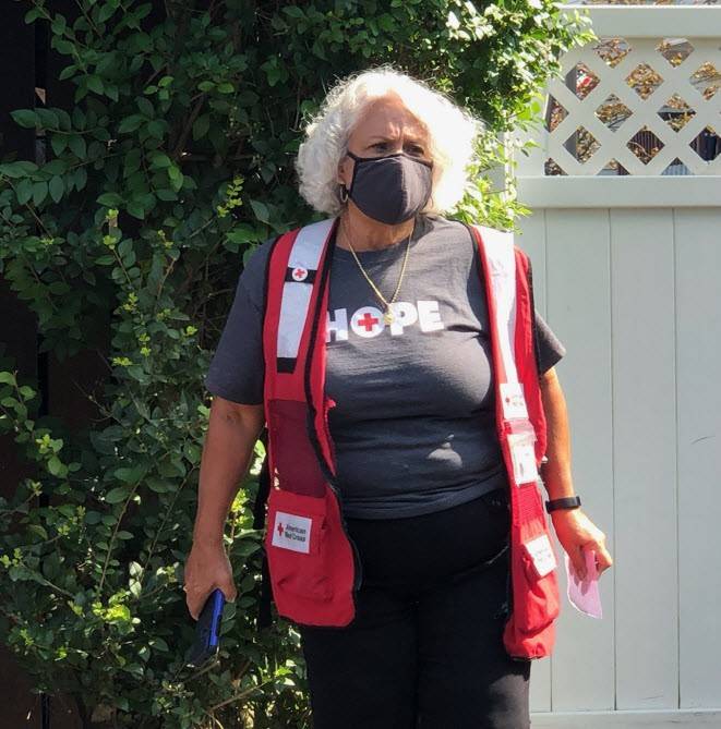 Red Cross volunteer wearing a mask and Red Cross vest and shirt.