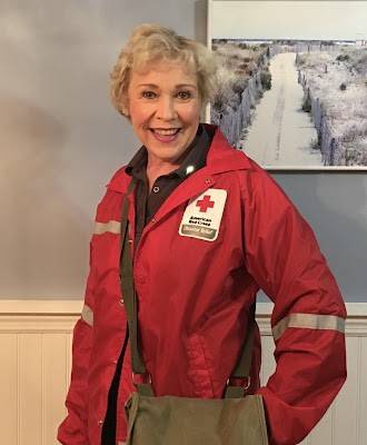 Red Cross volunteer wearing a Red Cross jacket and a purse while smiling for picture.