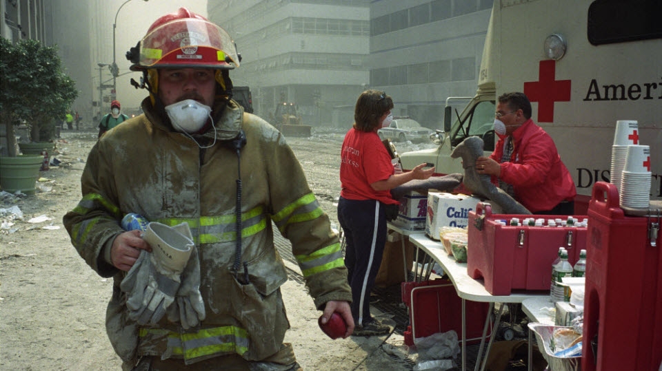 Firefighter walks by a Red Cross volunteer who is providing relief items from an emergency response vehicle.