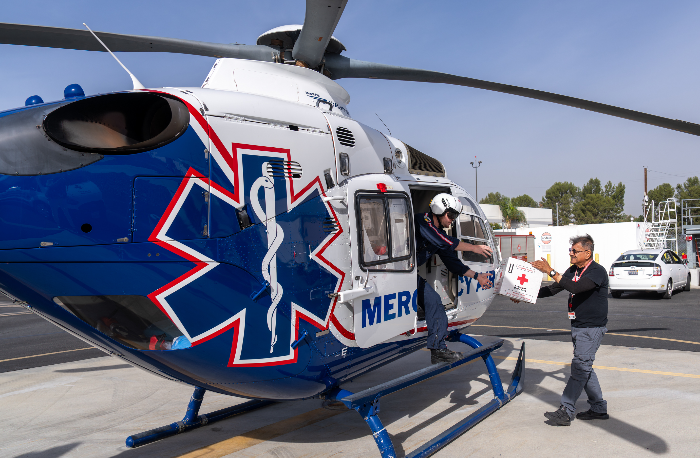 Ernie handing a blood packet shipment to a helicopter pilot.