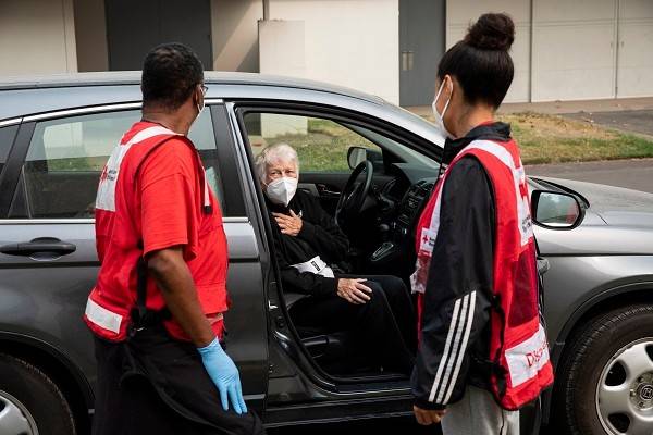 Red Cross volunteers say goodbye to Juanita Ann Hamann who's sitting in a car as she leaves a Red Cross shelter.