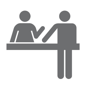 Two people talking at desk icon.