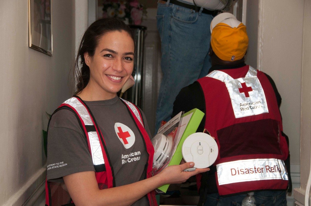 American Red Cross volunteer holding smoke alrams and smiling.